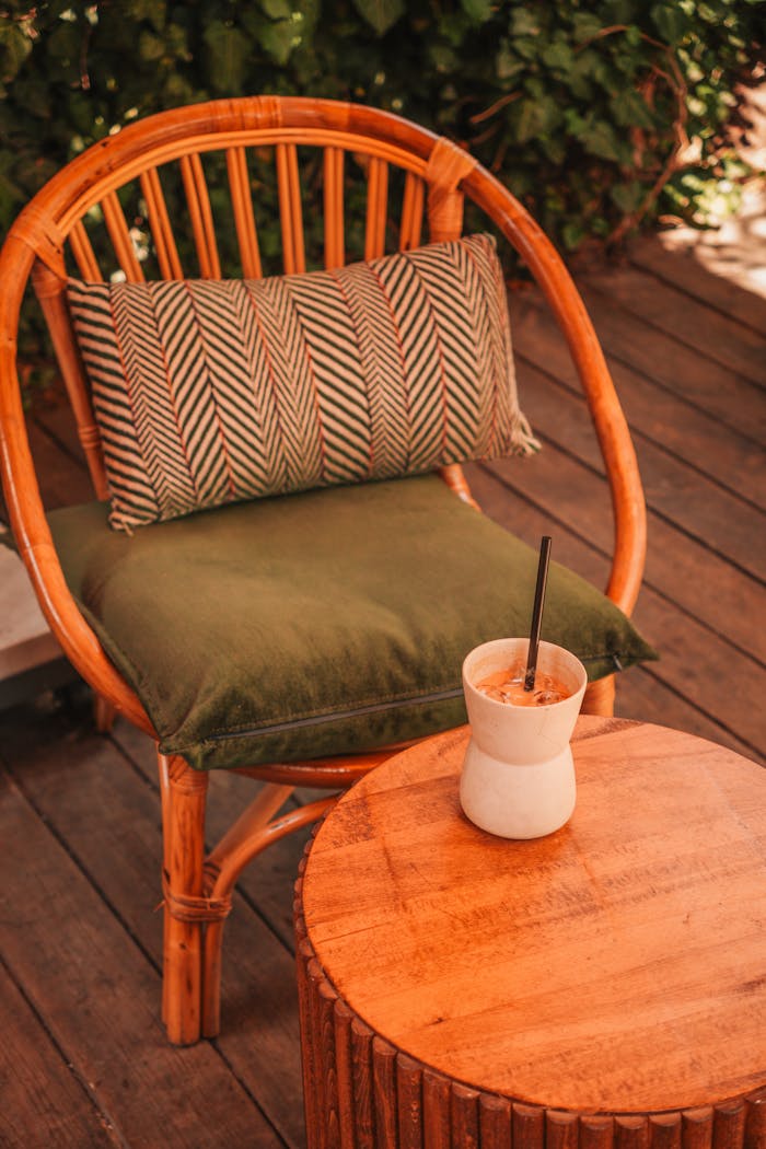 Services-02 Bamboo chair with cushion and refreshing drink on a wooden patio, relaxing outdoor setting.
